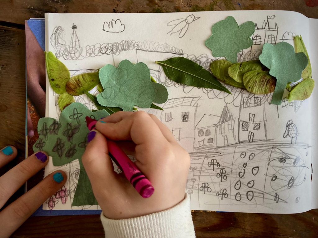 Child's hand drawing on leaves in a sketchbook