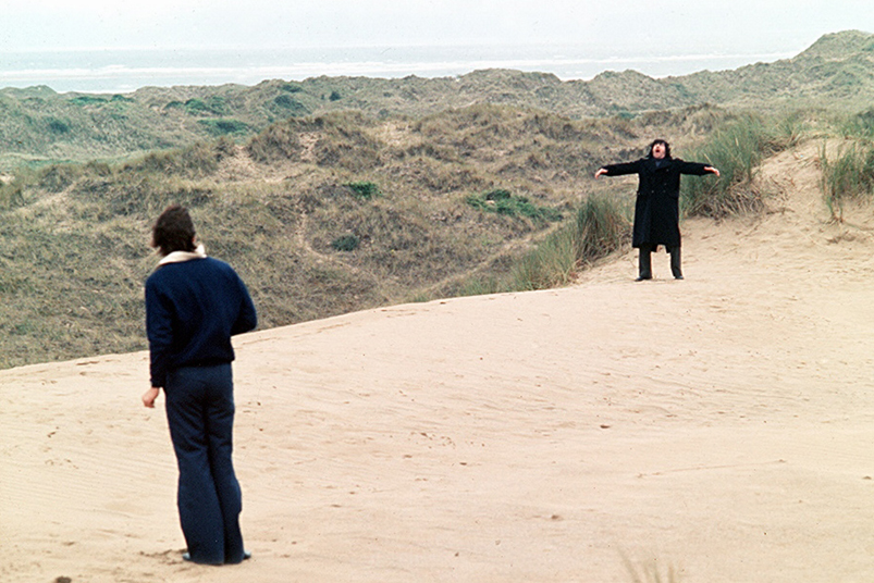 Two people dressed in black in sand dunes