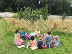 A group of children sit in a circle on grass
