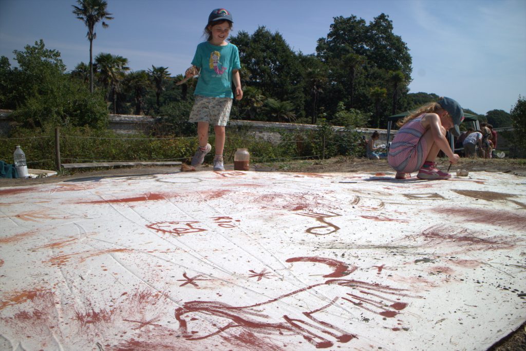 A large canvas being drawn on by children outside