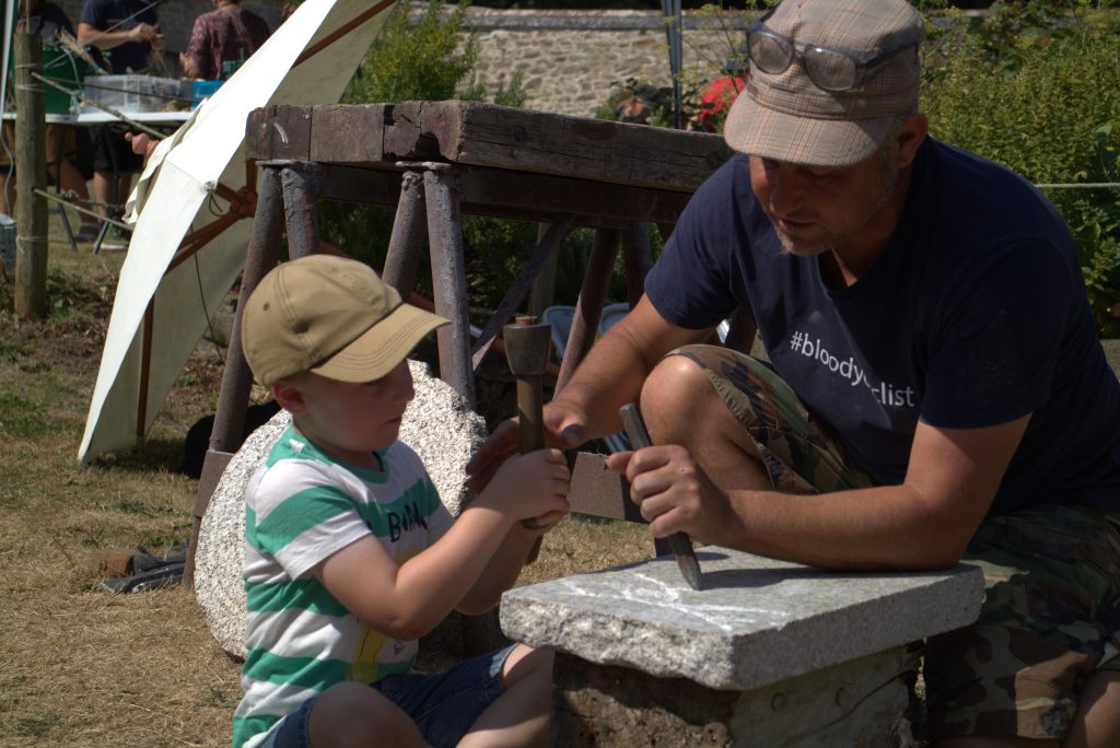 A man helps a child carve stone
