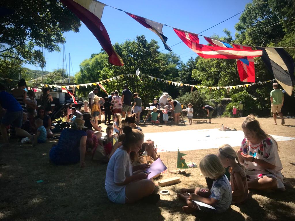 A group of families sit underneath nautical flags