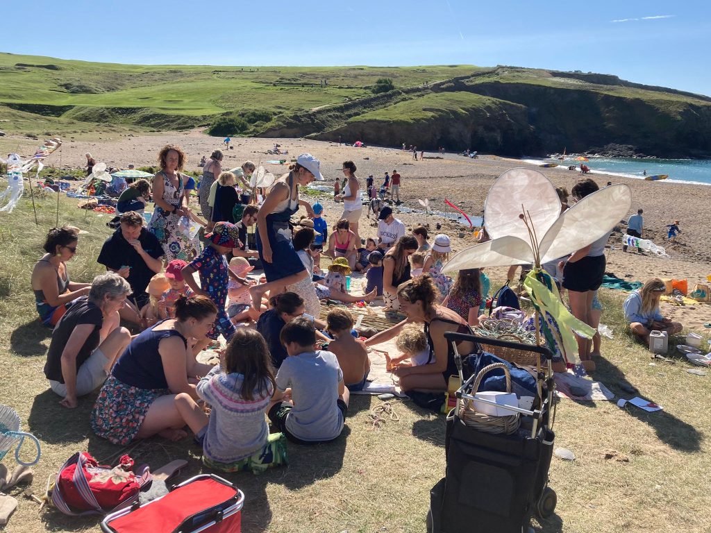 A large group of families on a beach making crafts