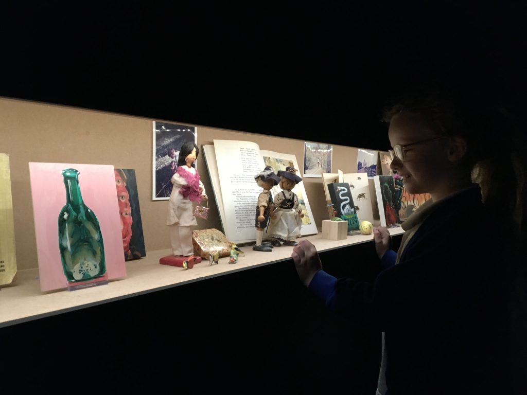 A child looks at an illuminated cabinet of curiosities