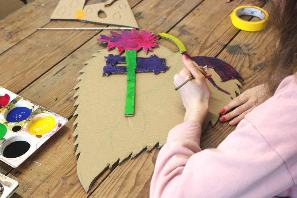 A close-up of someone making a cardboard mask.