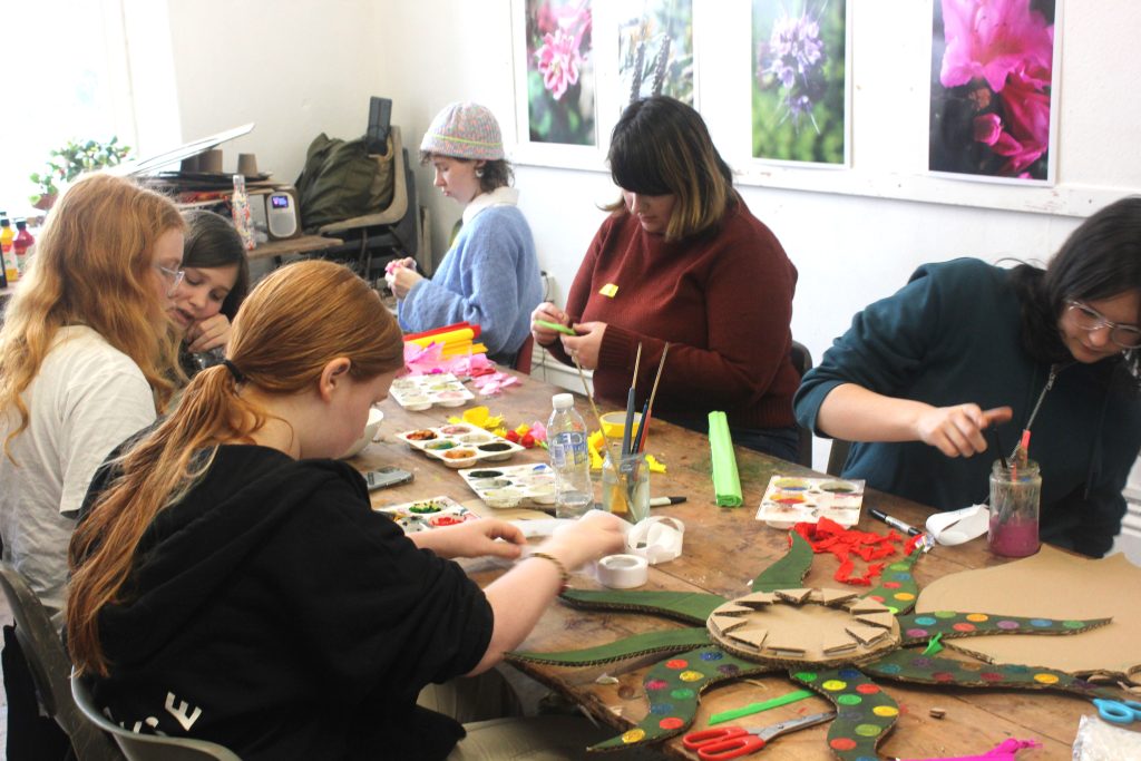 A group of young people making colourful masks from cardboard.