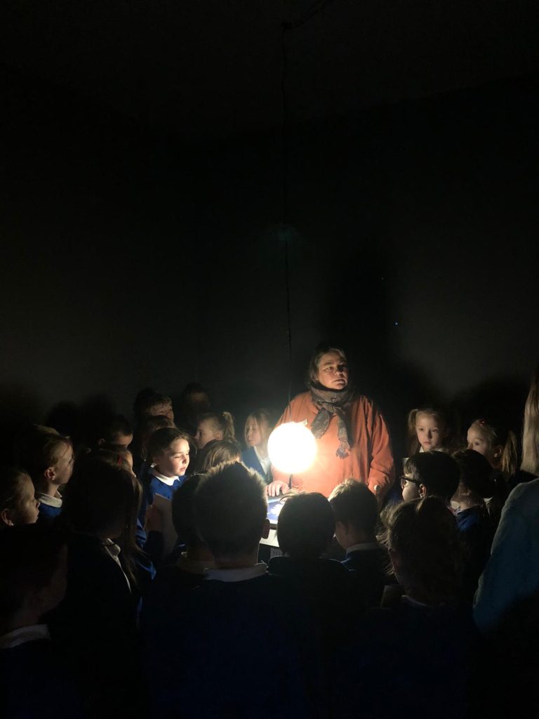 Children gather around a light in a dark space