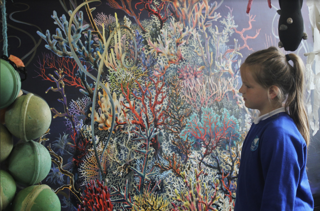 A child looks at a an elaborate painting of coral