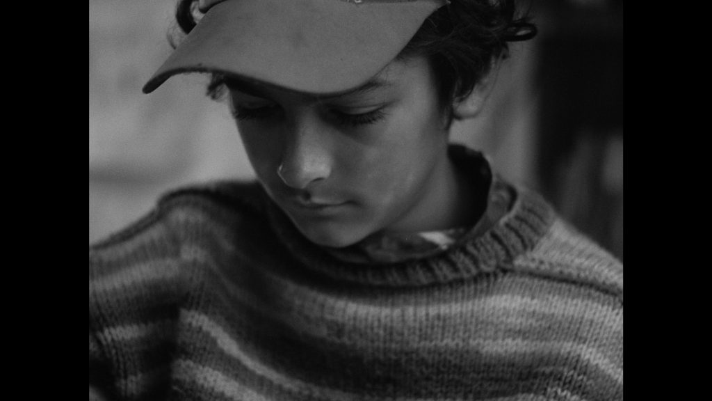 Black and white image of a young boy in a baseball cap