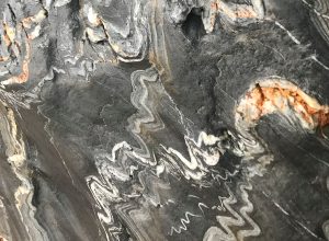 Close up of white wave formations within grey stone. 