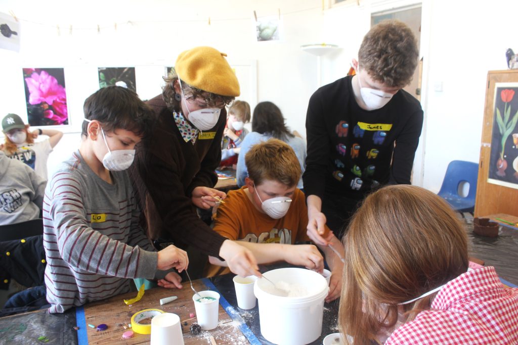 Four young people in dust masks mixing plaster