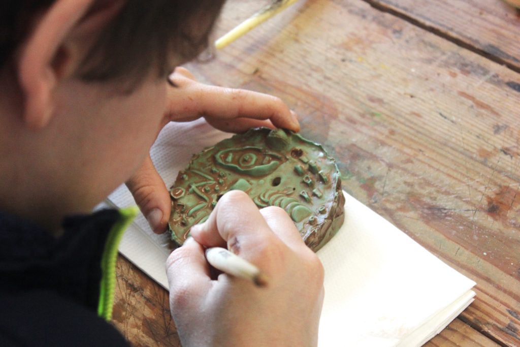 A young person carving a small medallion