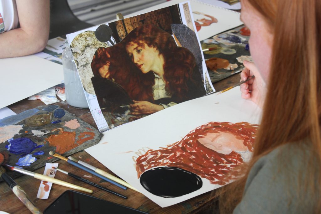 A person painting a woman with flowing hair